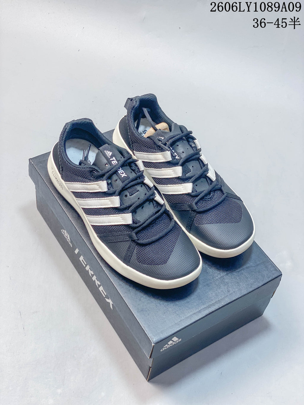 Navy Adidas Climacool lace-up shoes with off-white side stripes and soles, pictured on a Terrex box.