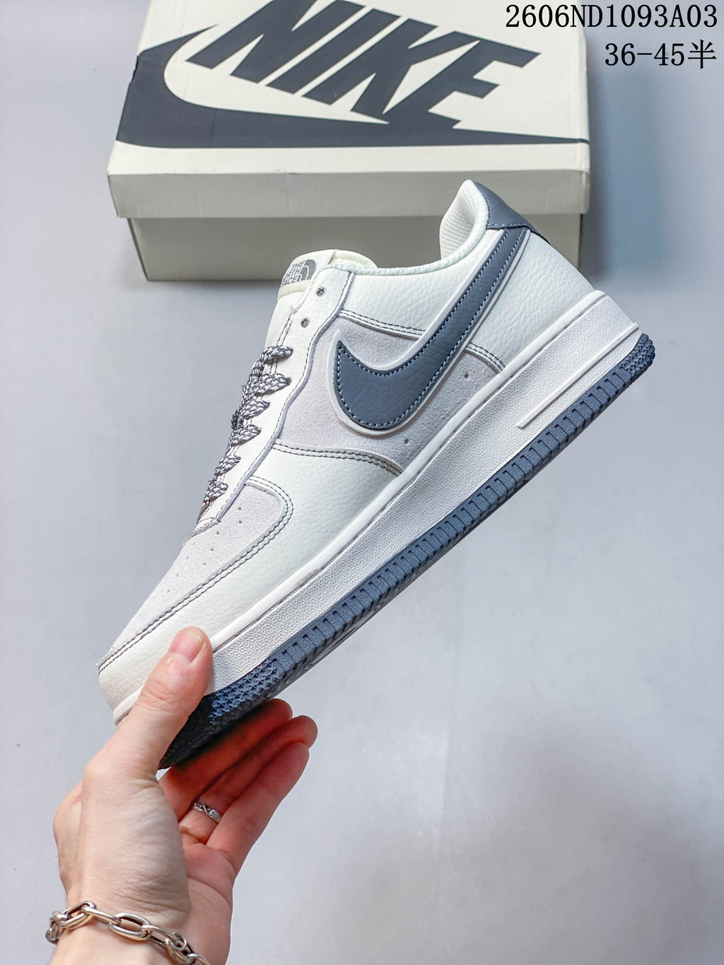 Side view of the white and grey low-top sneaker with contrasting side panel and outsole