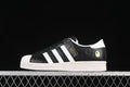 Side view of a black and white adidas Superstar sneaker with embossed upper and gold-tone accents