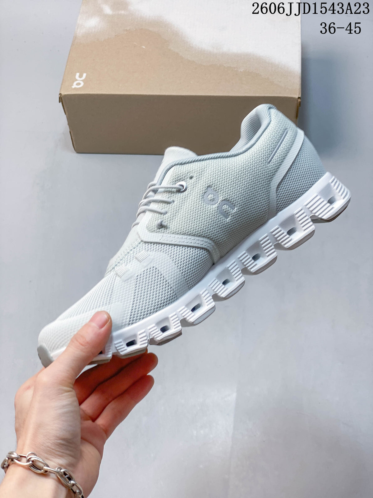 Side view of a light-colored On Cloudtilt Remix sneaker with a segmented outsole