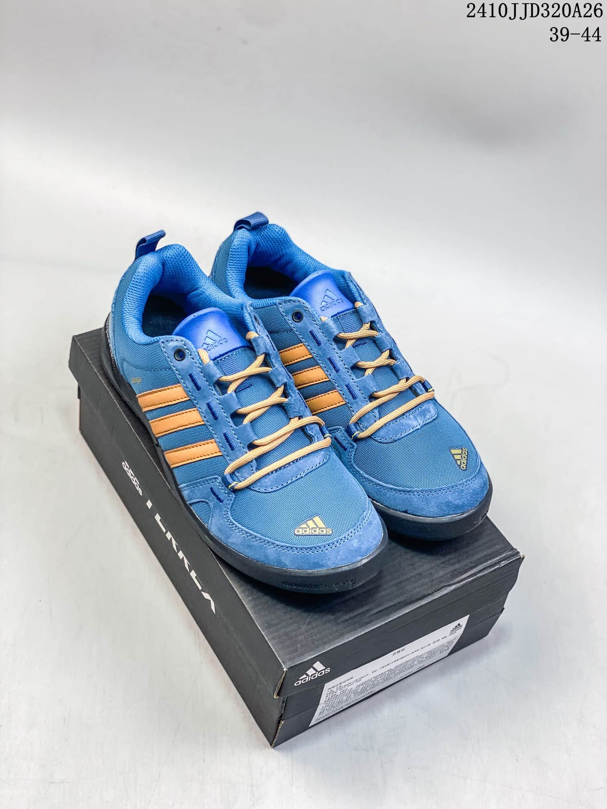 Blue adidas Daroga Plus shoes with tan stripes shown on a shoebox