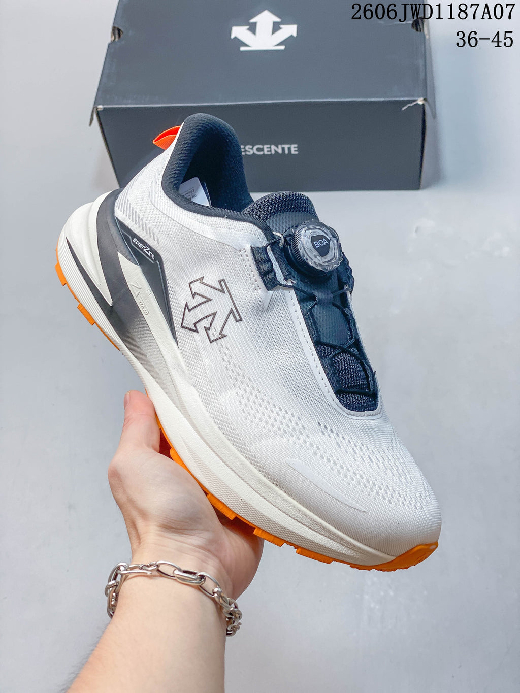 Angled side view of the shoe showing the DESCENTE logo, dial closure, and orange outsole