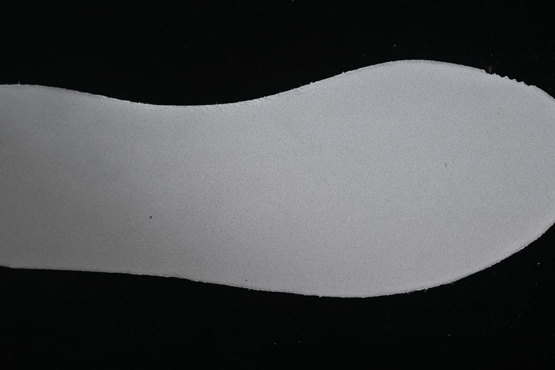 Light-colored shoe-shaped insert photographed on a dark background