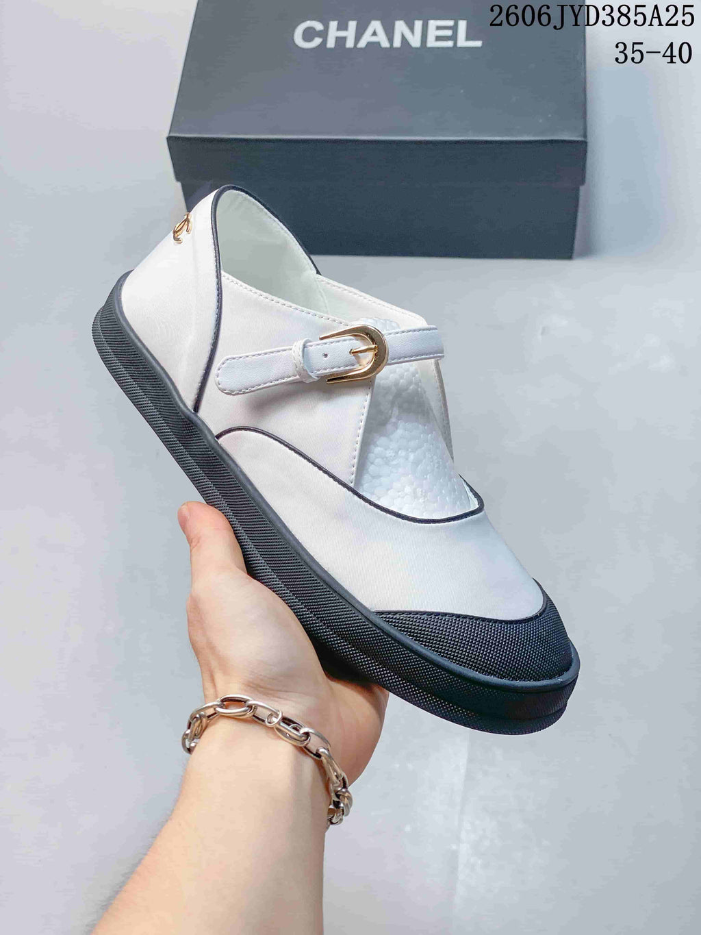 Side view of a white Mary Jane flat with dark trim, a buckle strap, and a low sole; size range 35–40 shown.