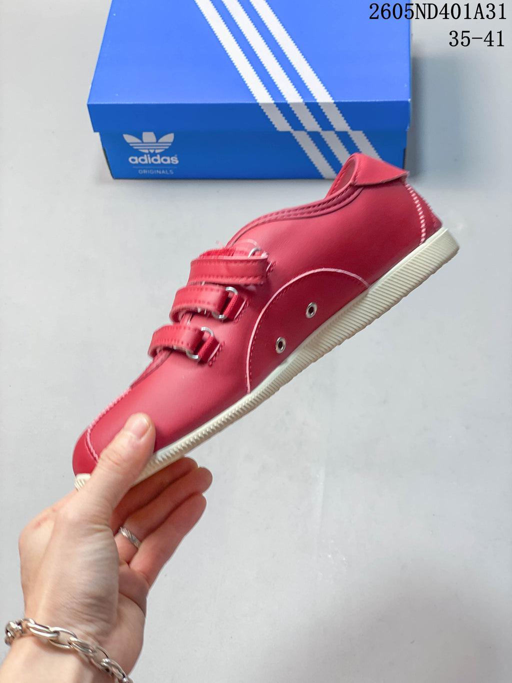 Side view of the red low-top sneaker with multiple straps and white stripes