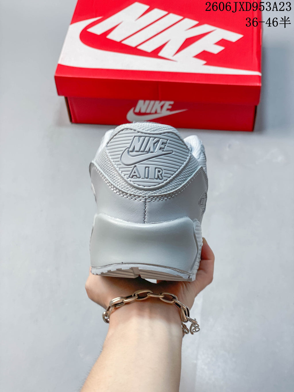 Rear view of a light grey Nike Air Max 90 sneaker showing the heel panel