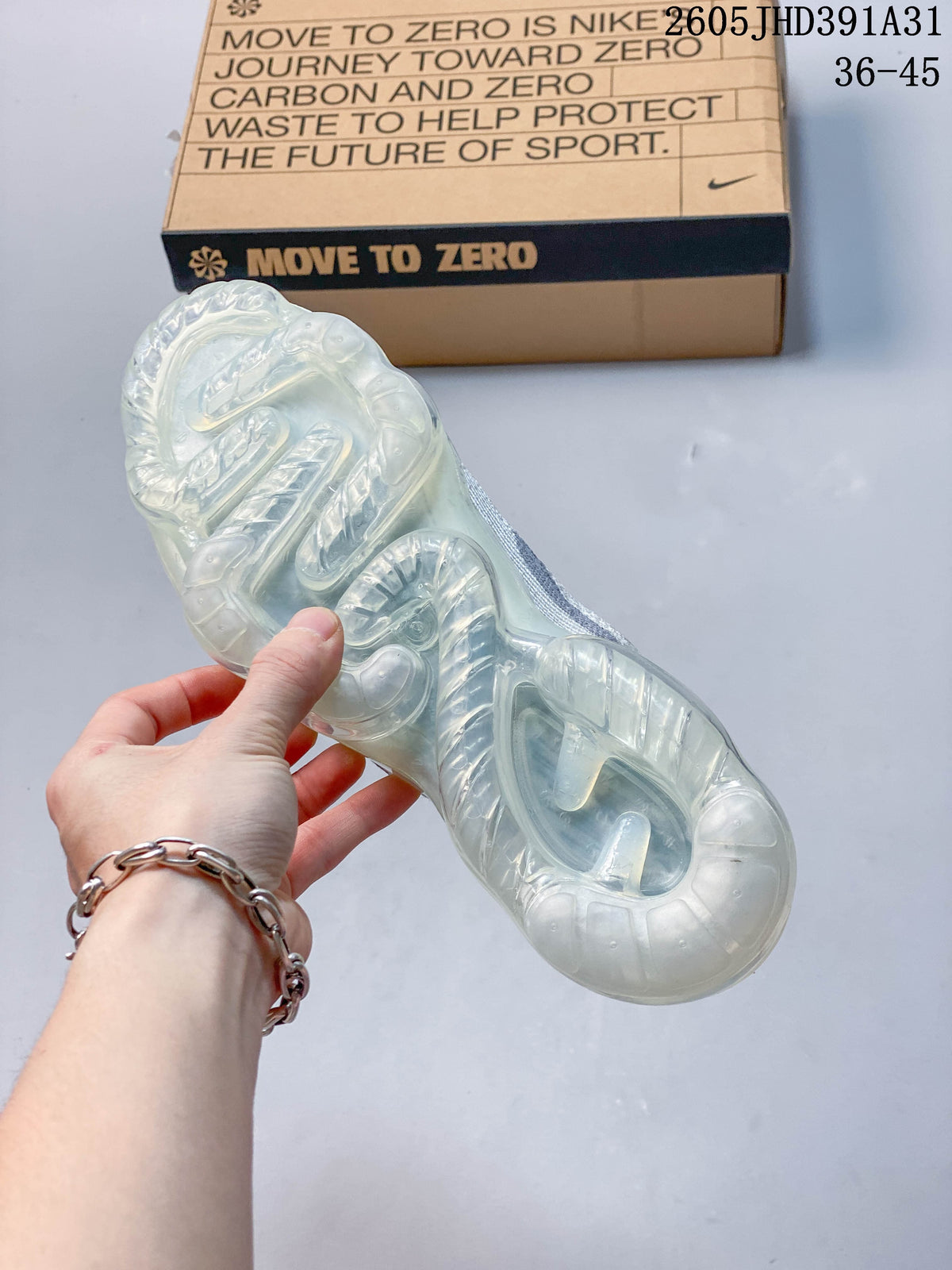 Underside view of a shoe showing its translucent full-length sole, with a shoebox in the background.