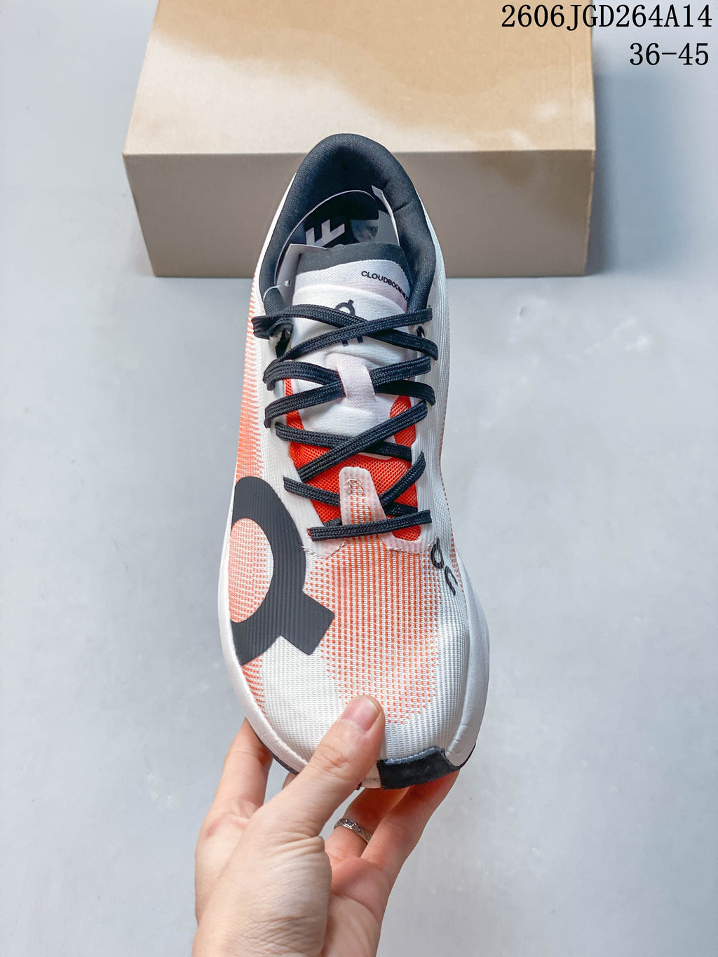 Top view of an ivory-white On Cloudboom Volt shoe with coral details and dark laces