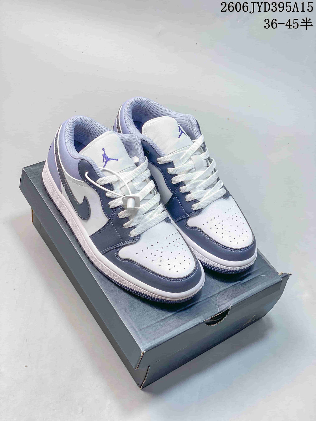 Pair of white and muted blue-gray Jordan low-top sneakers on a shoebox