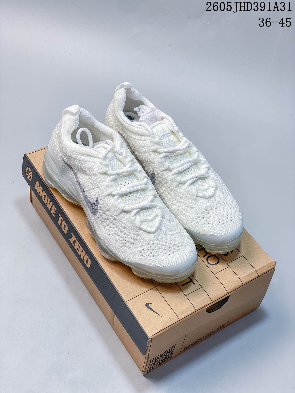 Pair of white Nike Air VaporMax 2023 Flyknit shoes on a shoebox; image overlay shows size range 36–45.