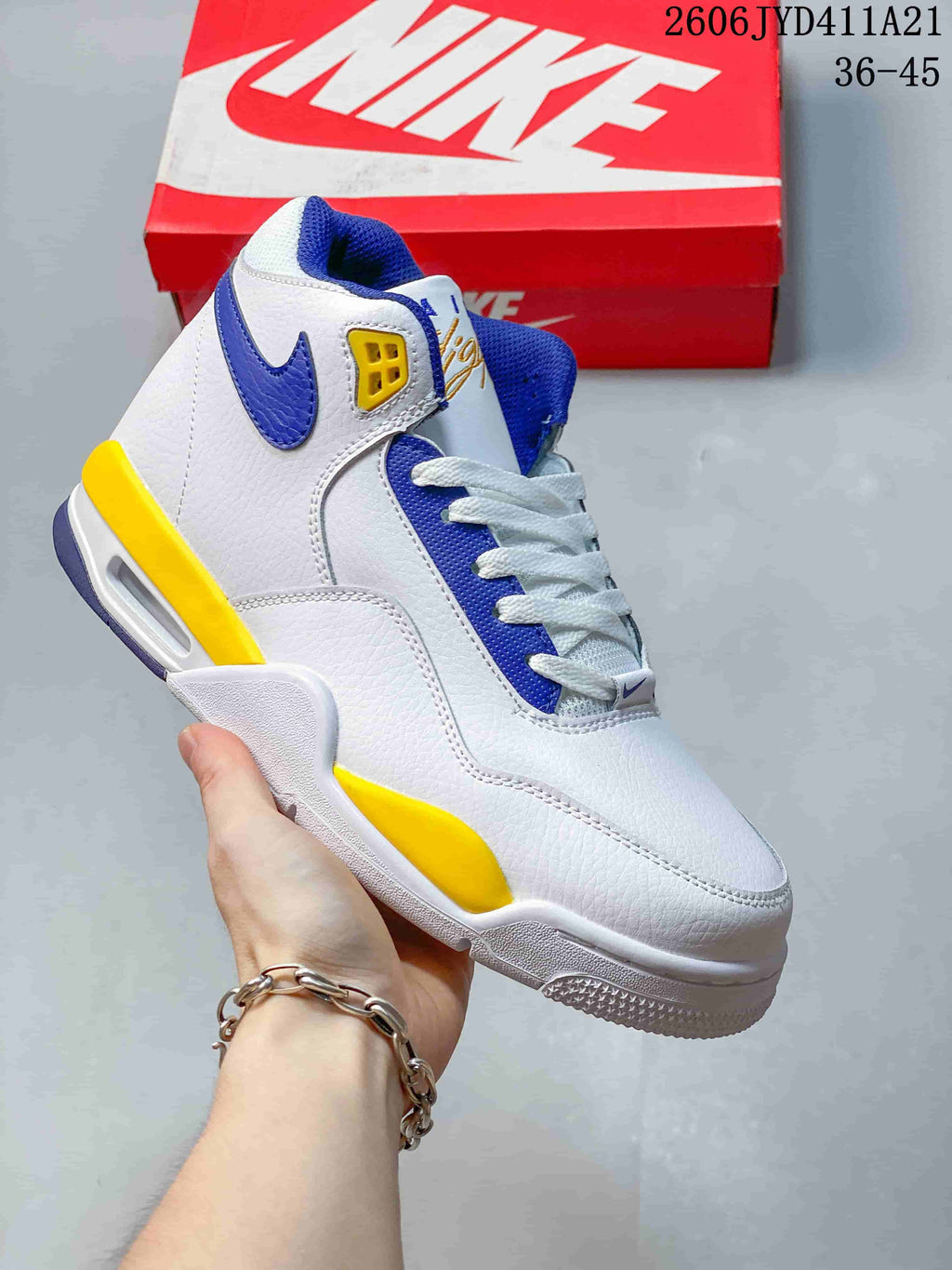 Side view of a white Nike Flight Legacy mid-top sneaker with blue and yellow accents