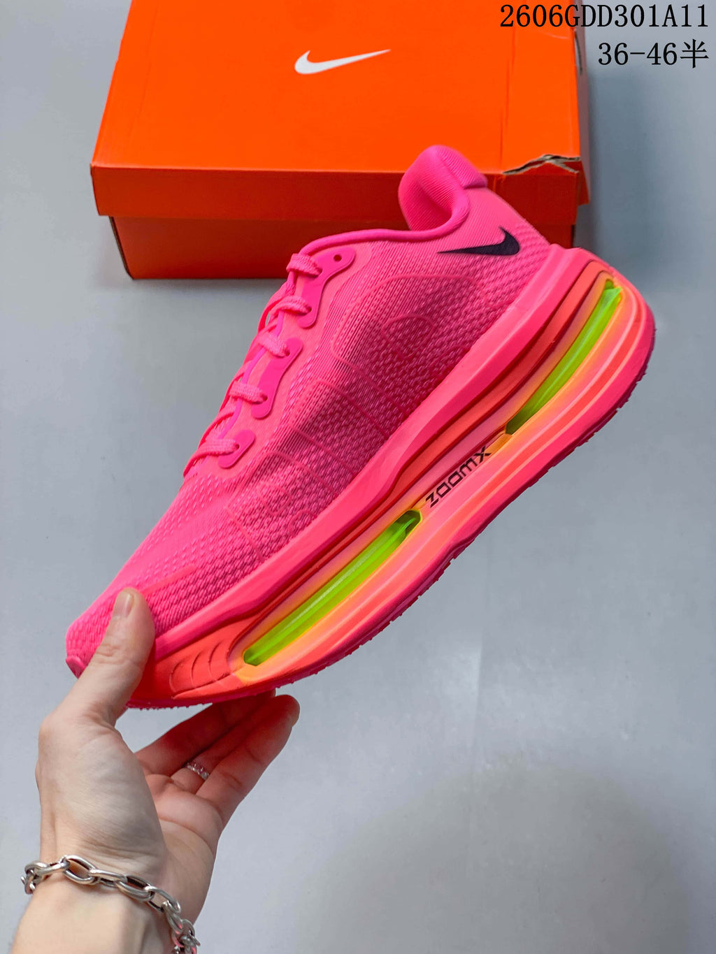 Side profile of a hot-pink Nike Vomero Premium running shoe with black Swoosh and bright accents in the thick sole.