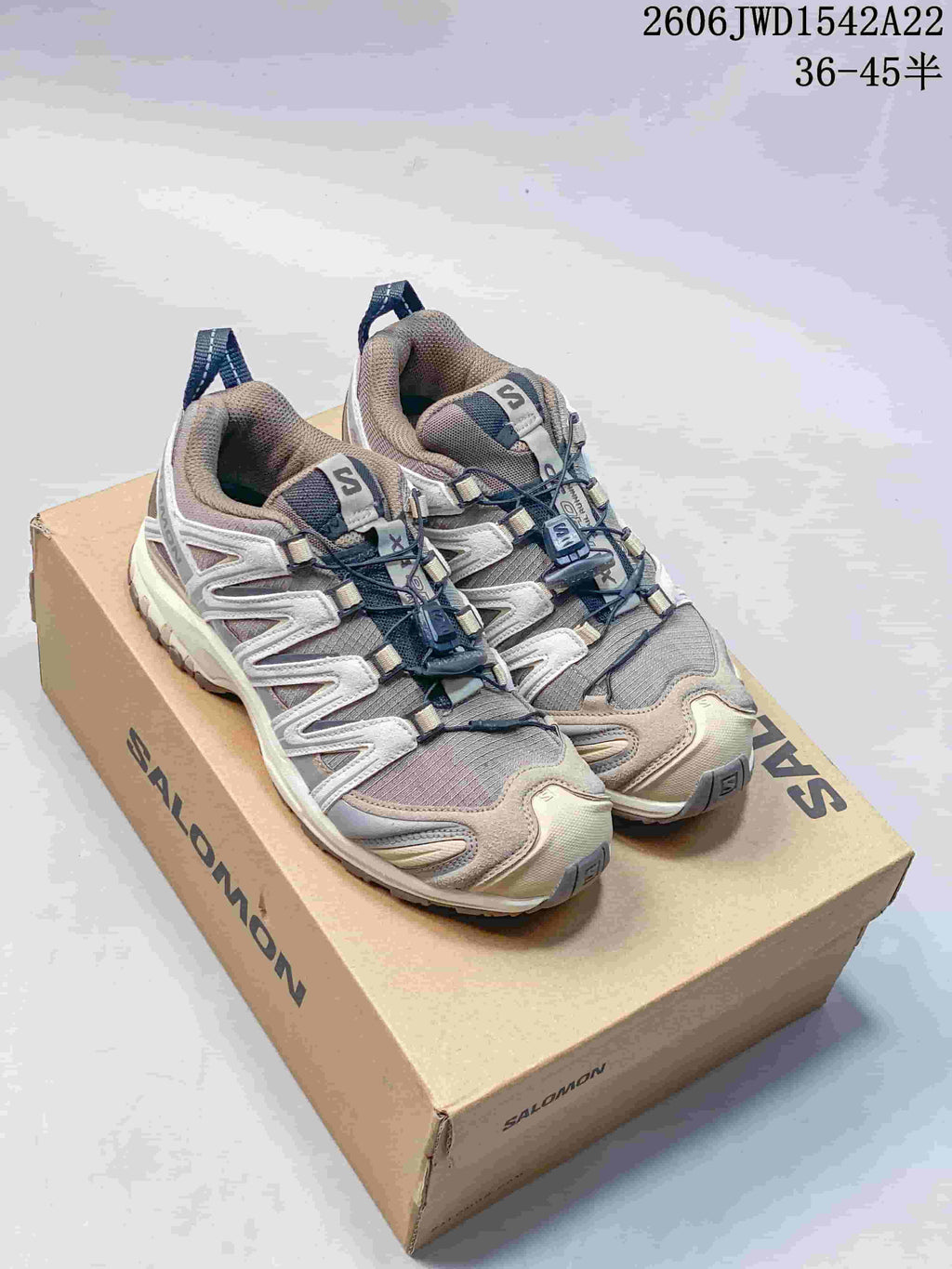 Pair of taupe and gray Salomon XA Pro 3D sneakers on a branded box.