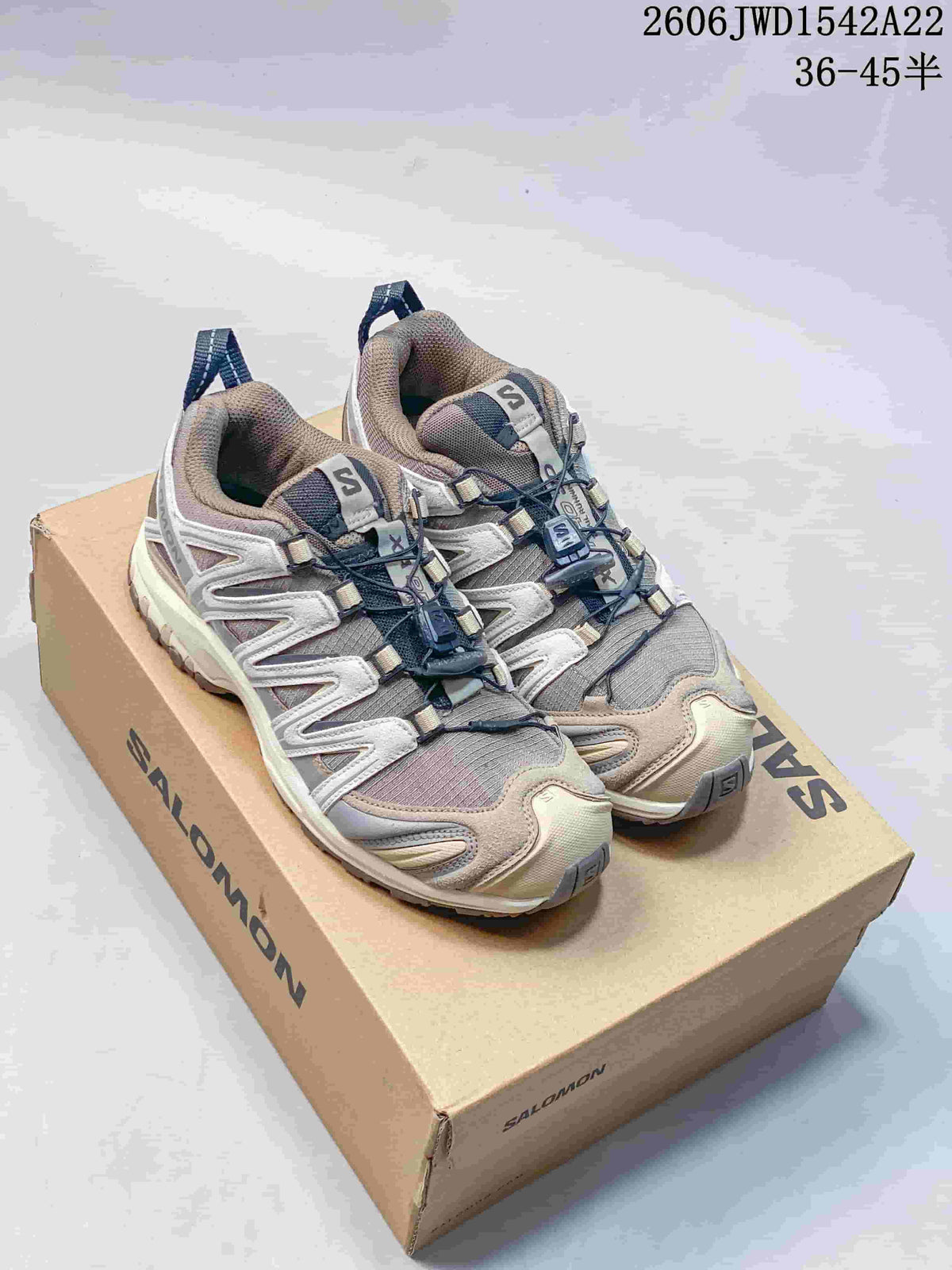 Pair of taupe and gray Salomon XA Pro 3D sneakers on a branded box.