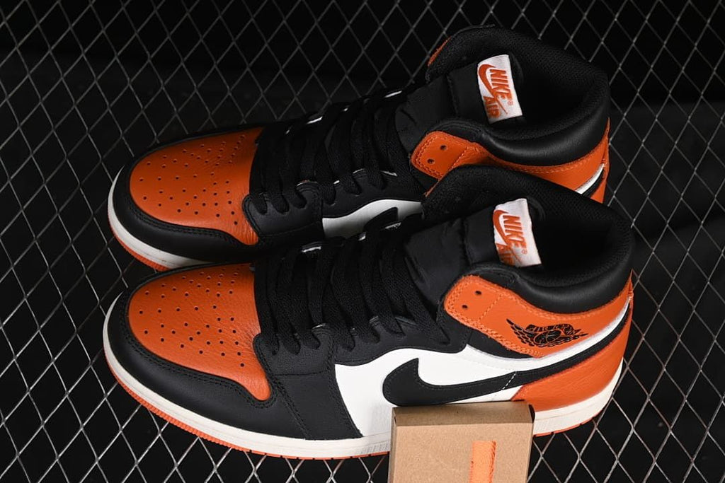 Pair of orange, black and white high-top sneakers displayed together