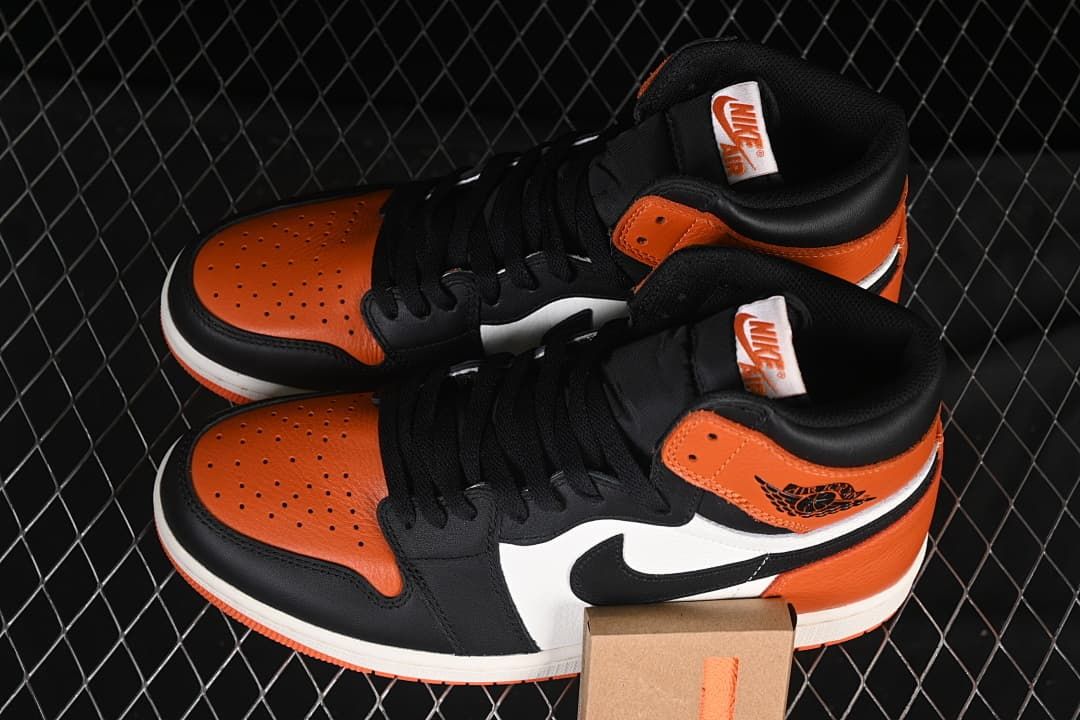 Pair of orange, black and white high-top sneakers displayed together
