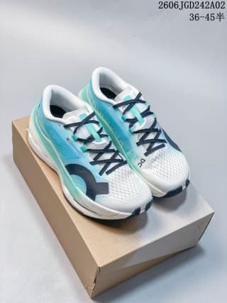 Pair of turquoise and white ON Cloudboom Max sneakers displayed on top of a shoe box.