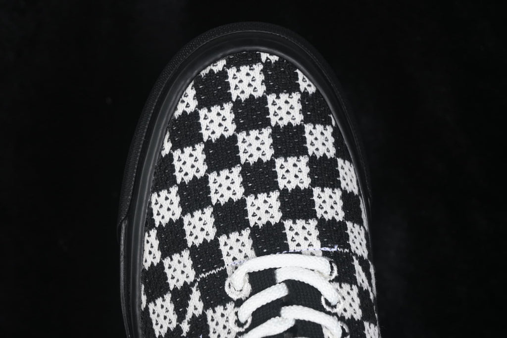 Close-up of the black-and-white checkerboard toe with white laces and black rubber foxing.