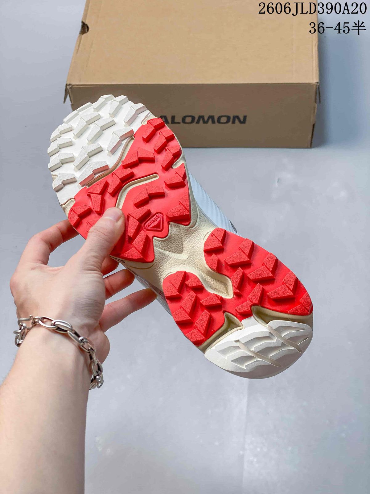 Close-up of the trail shoe outsole with prominent red and white lugs.