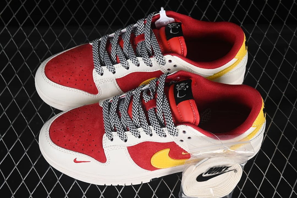 Overhead view of a pair of red, white, and yellow low-top sneakers with patterned laces.