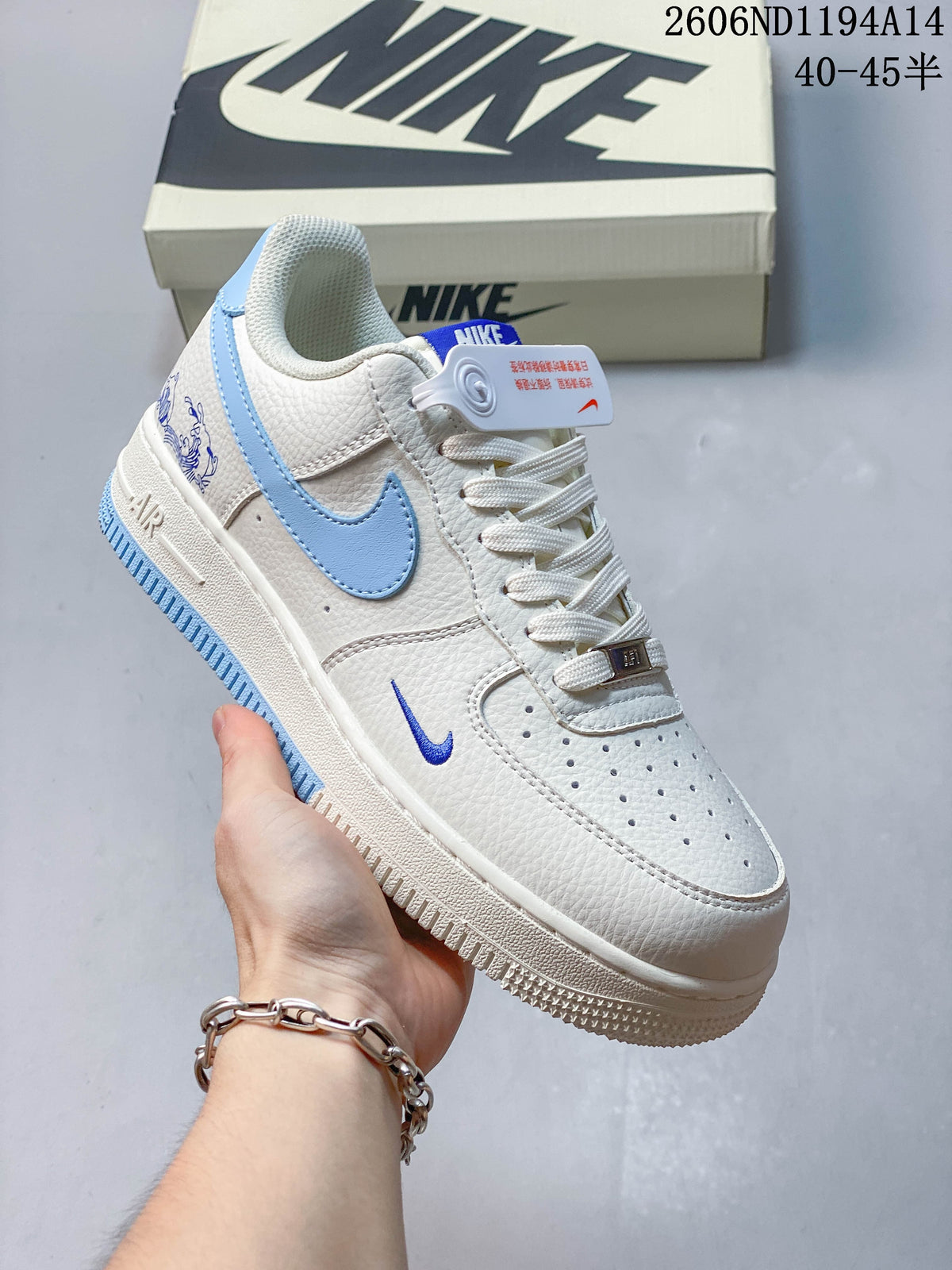 Close-up side view of a white Nike Air Force 1 '07 Low sneaker with light blue Swoosh accents.