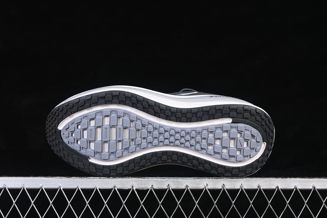Underside of the Nike Vomero Plus shoe showing its patterned black and gray outsole.