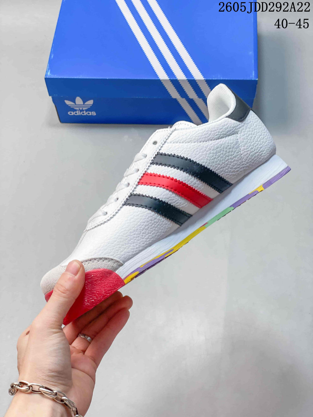 Side view of the white low-top sneaker with dark gray and red stripes and a multicolor outsole.