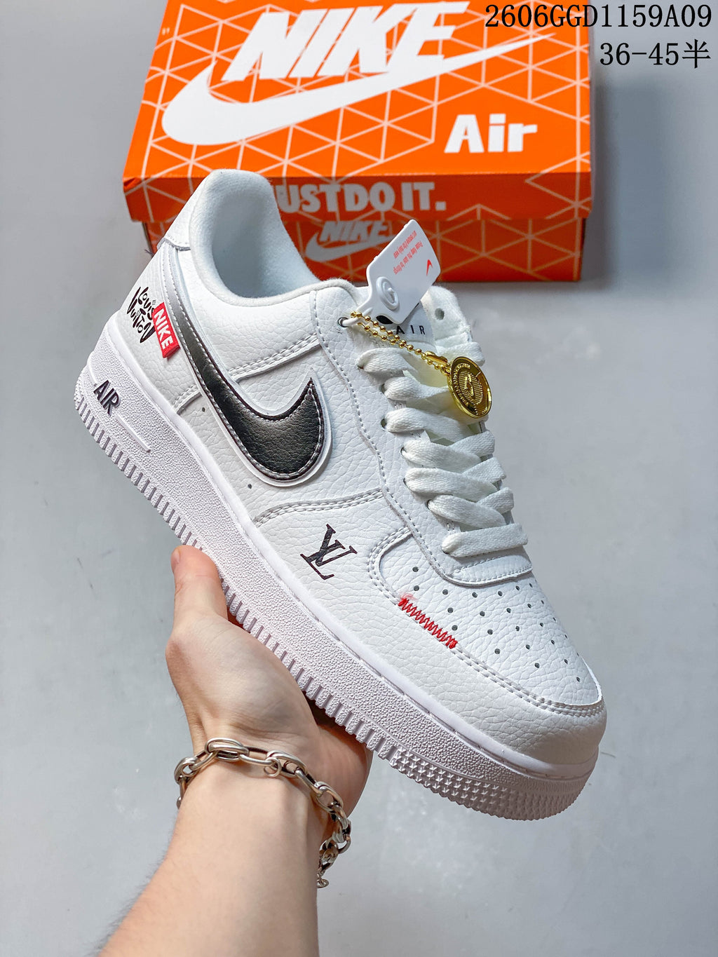Angled view of a white low-top sneaker with dark Swoosh, red details, and a gold-tone charm
