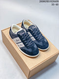 Pair of navy low-top lace-up sneakers with white branded ribbon-style side panels, pictured on a box.