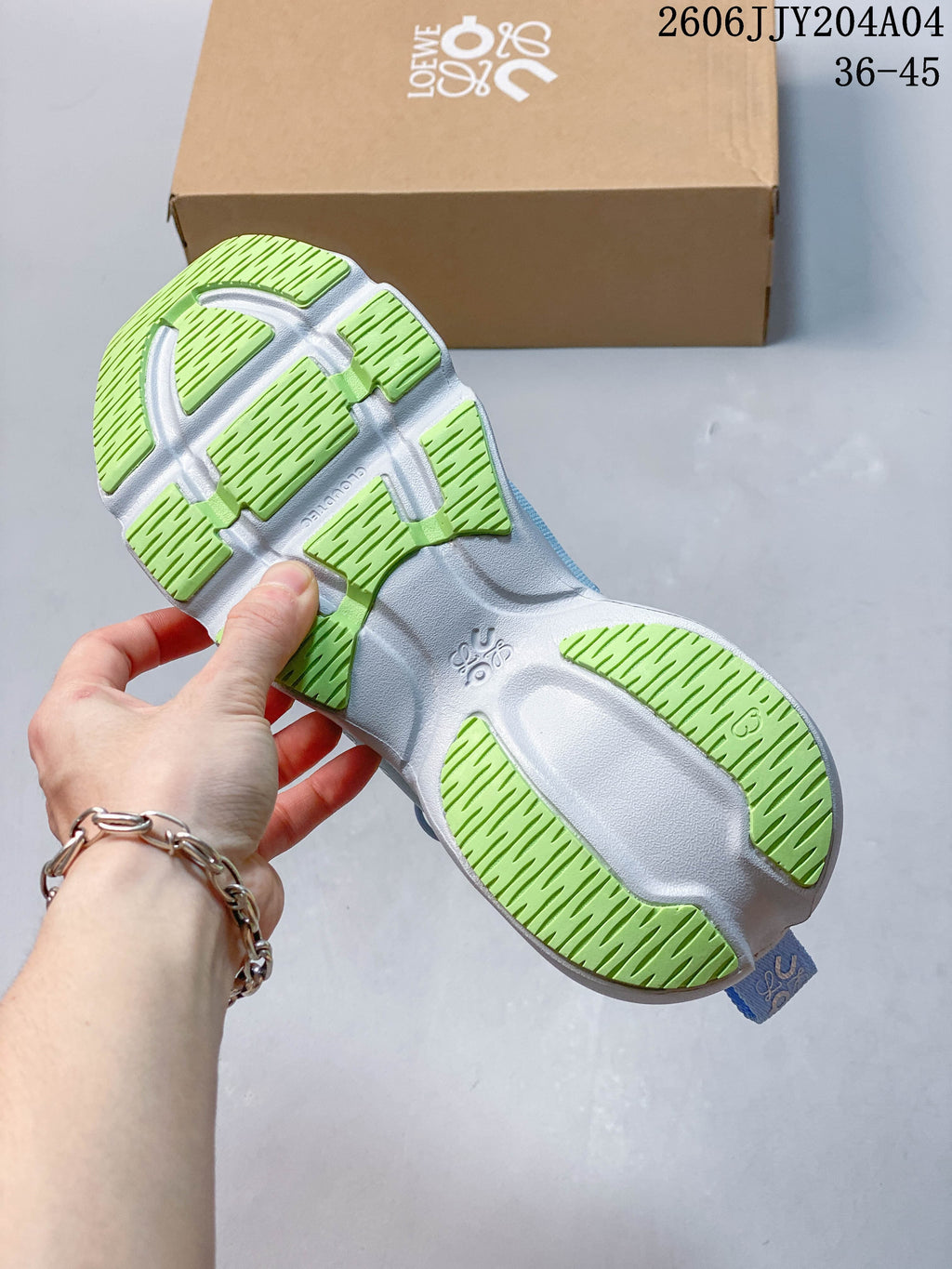 Underside of a sneaker showing a white sole with lime-green tread sections.