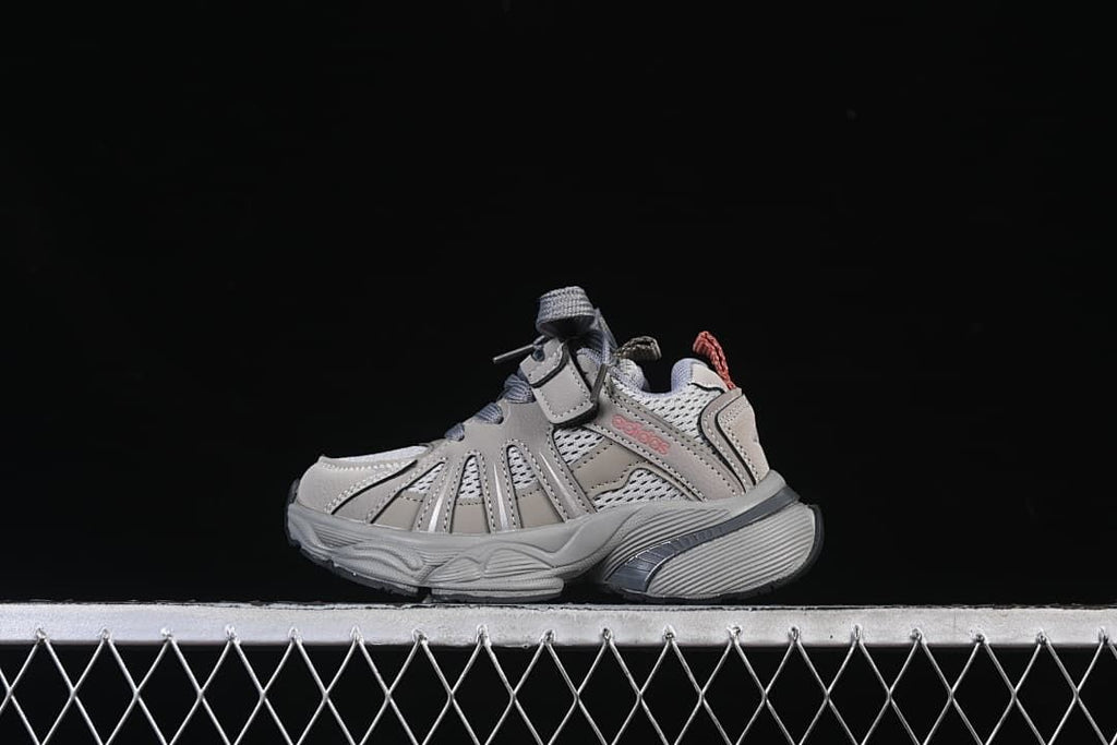 Side view of cement grey kids’ adidas Adistar sneakers against a dark background.