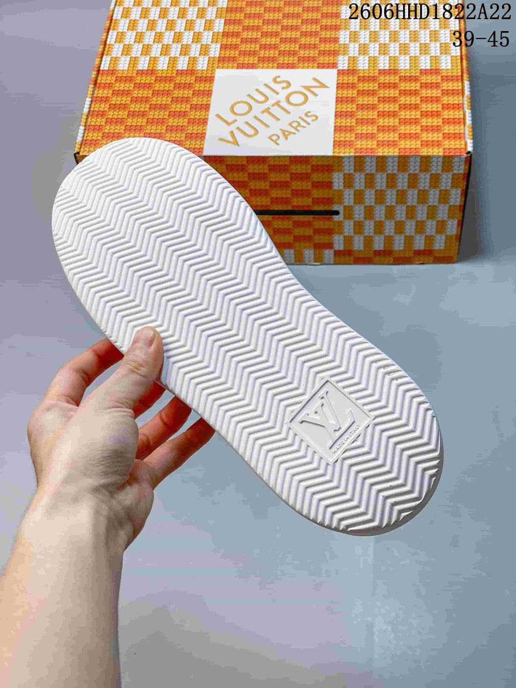 White outsole with a chevron tread pattern shown beside a patterned shoe box