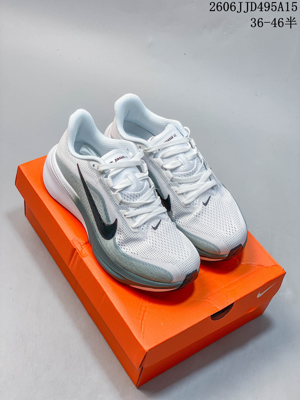 Pair of white and pale gray-green Nike Pegasus 42 running shoes on an orange box