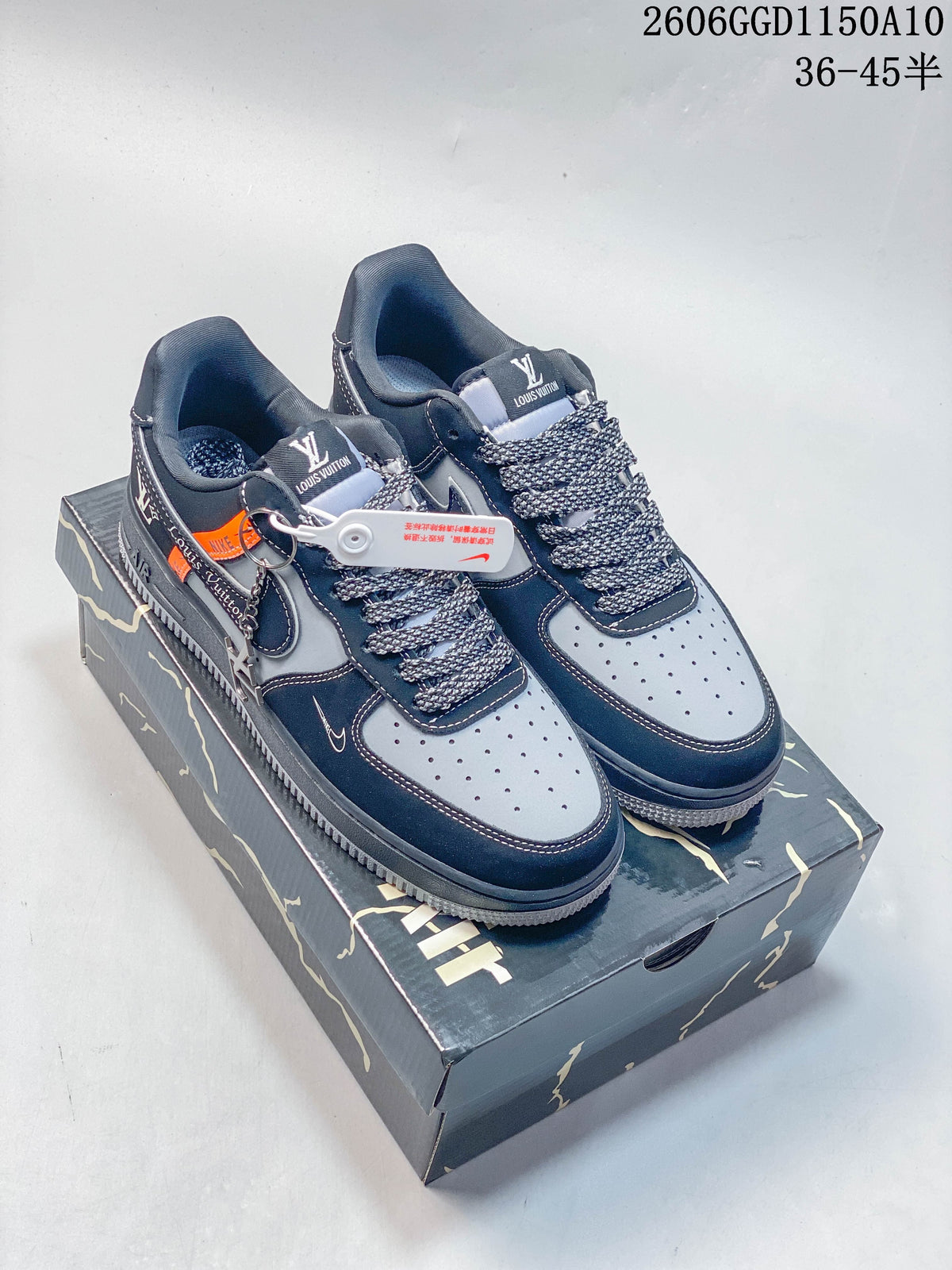 Pair of navy and gray low-top sneakers with patterned laces and orange accents, shown on a branded box