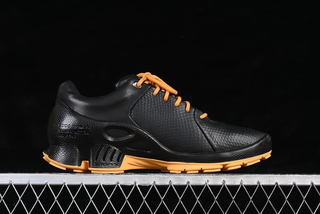 Side view of a black ECCO BIOM shoe with orange laces and outsole