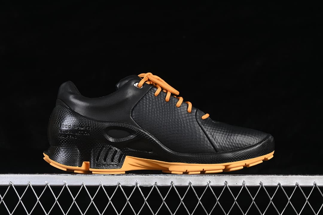 Side view of a black ECCO BIOM shoe with orange laces and outsole