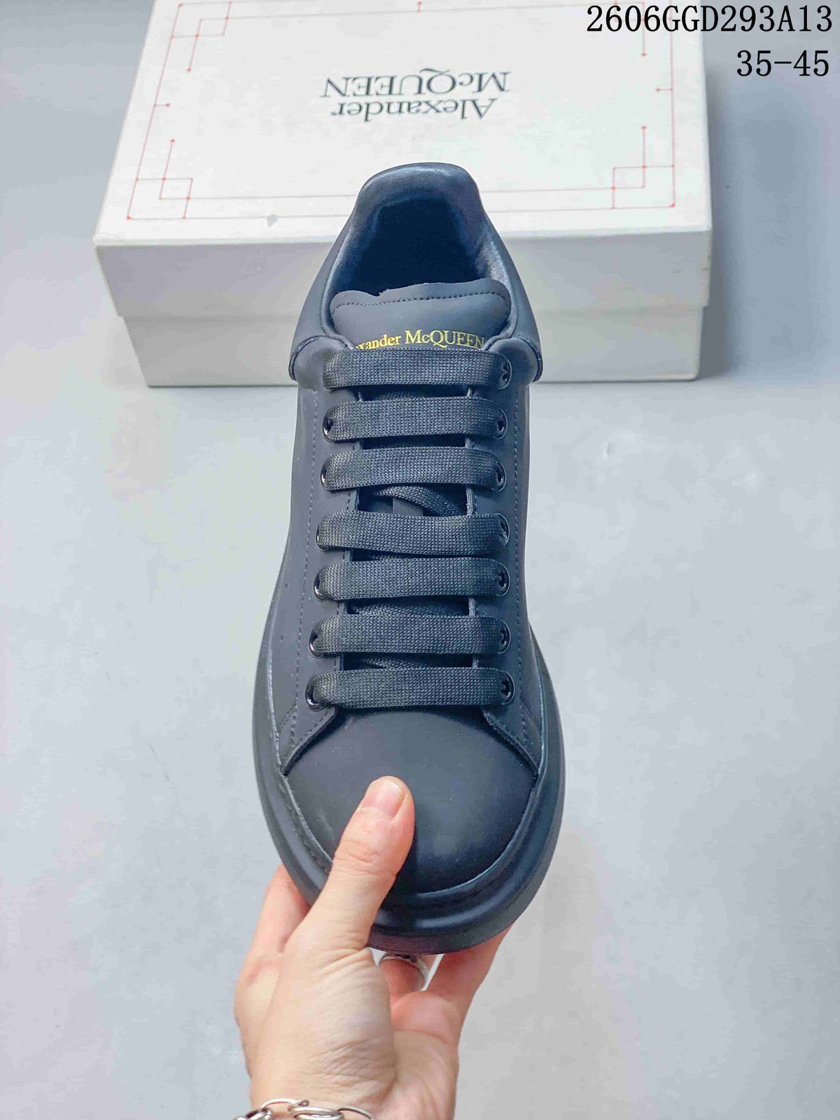 Front view of a dark charcoal sneaker with broad flat laces and a rounded toe.