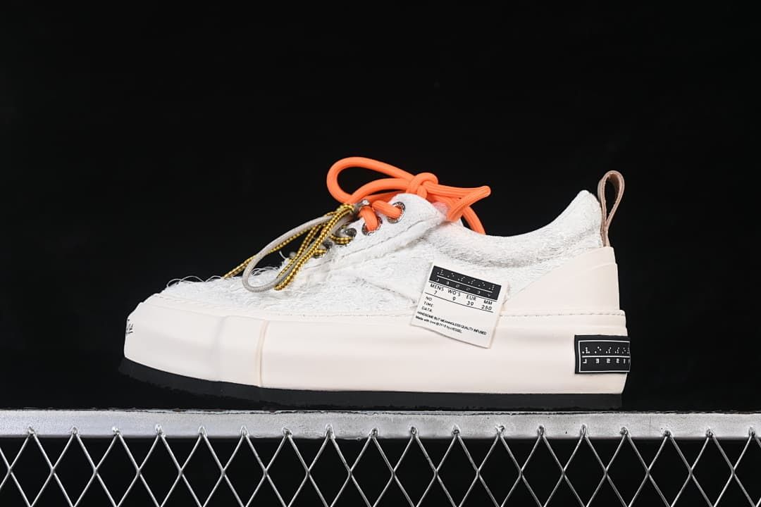 Side view of a white textured low-top platform sneaker with orange and patterned laces.