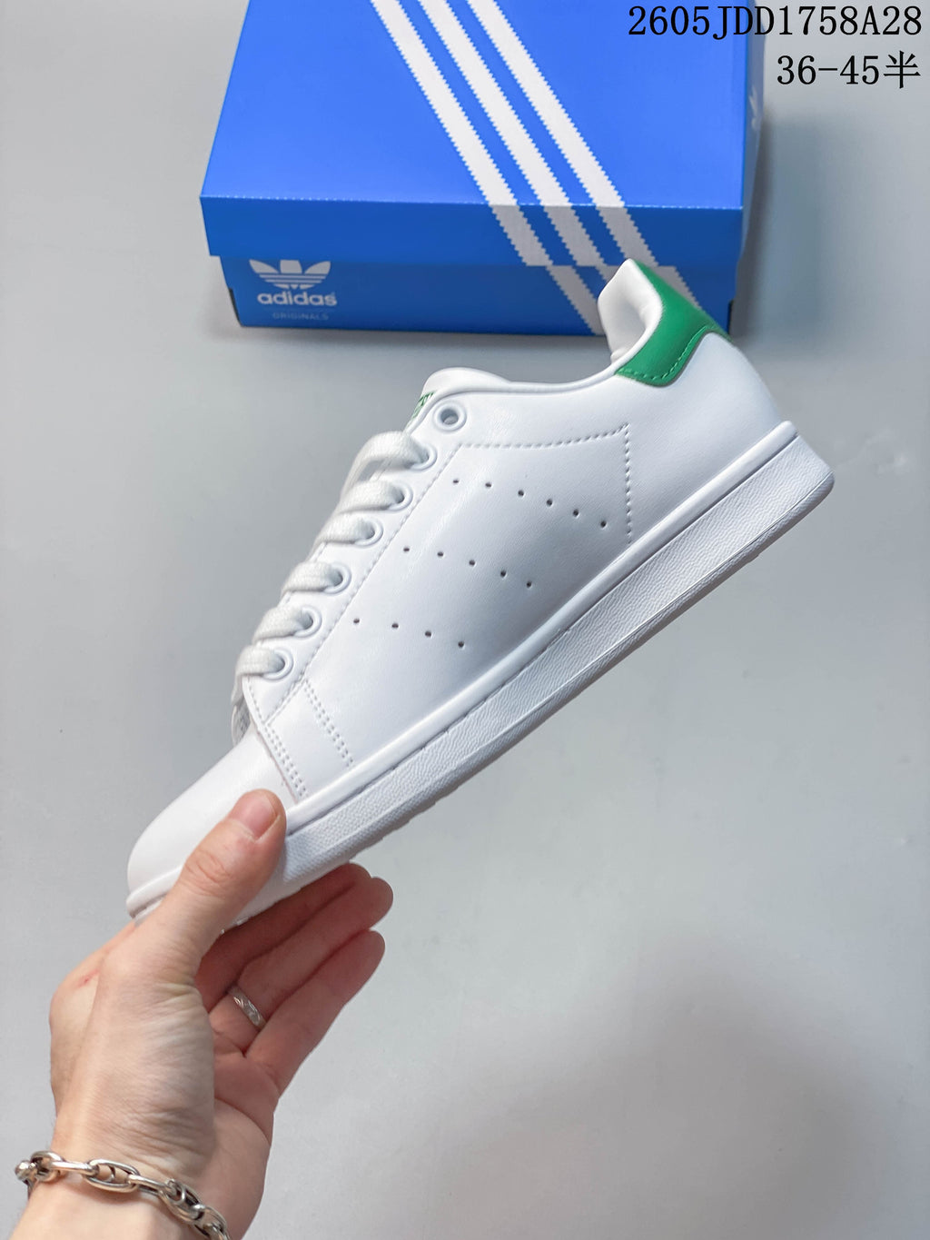 Side profile of a white low-top sneaker with perforated panels and green heel detail