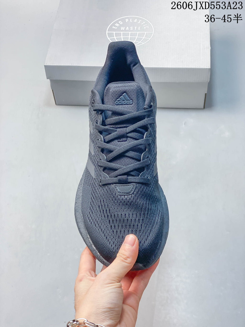 Top view of the lace-up front and mesh-like upper of a charcoal Adidas PureBoost 21 shoe.