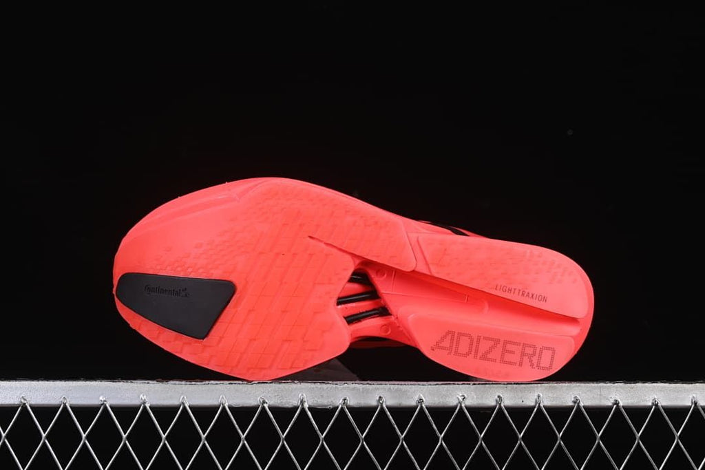 Underside of the coral shoe showing the outsole and Adizero text