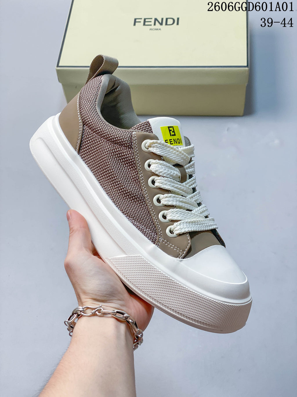 Angled view of a taupe and brown low-top sneaker with white laces and a thick white sole