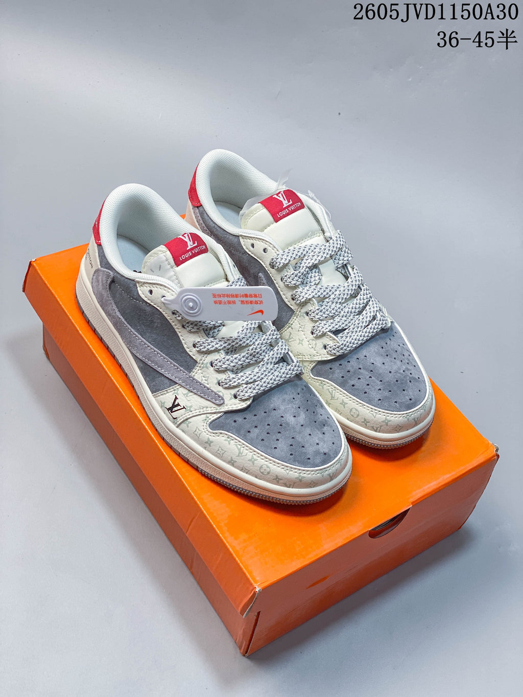 Pair of grey and off-white low-top sneakers with patterned panels and red accents, shown on an orange box