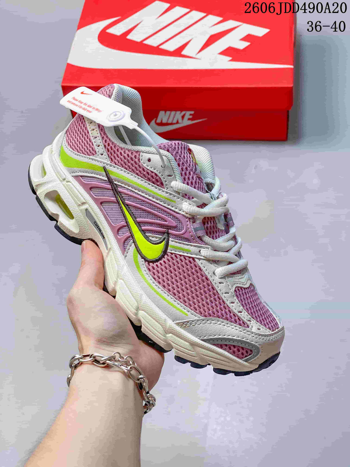 Angled side view of a Nike Air Max Moto 2K sneaker with pink mesh, lime accents, and a visible heel window