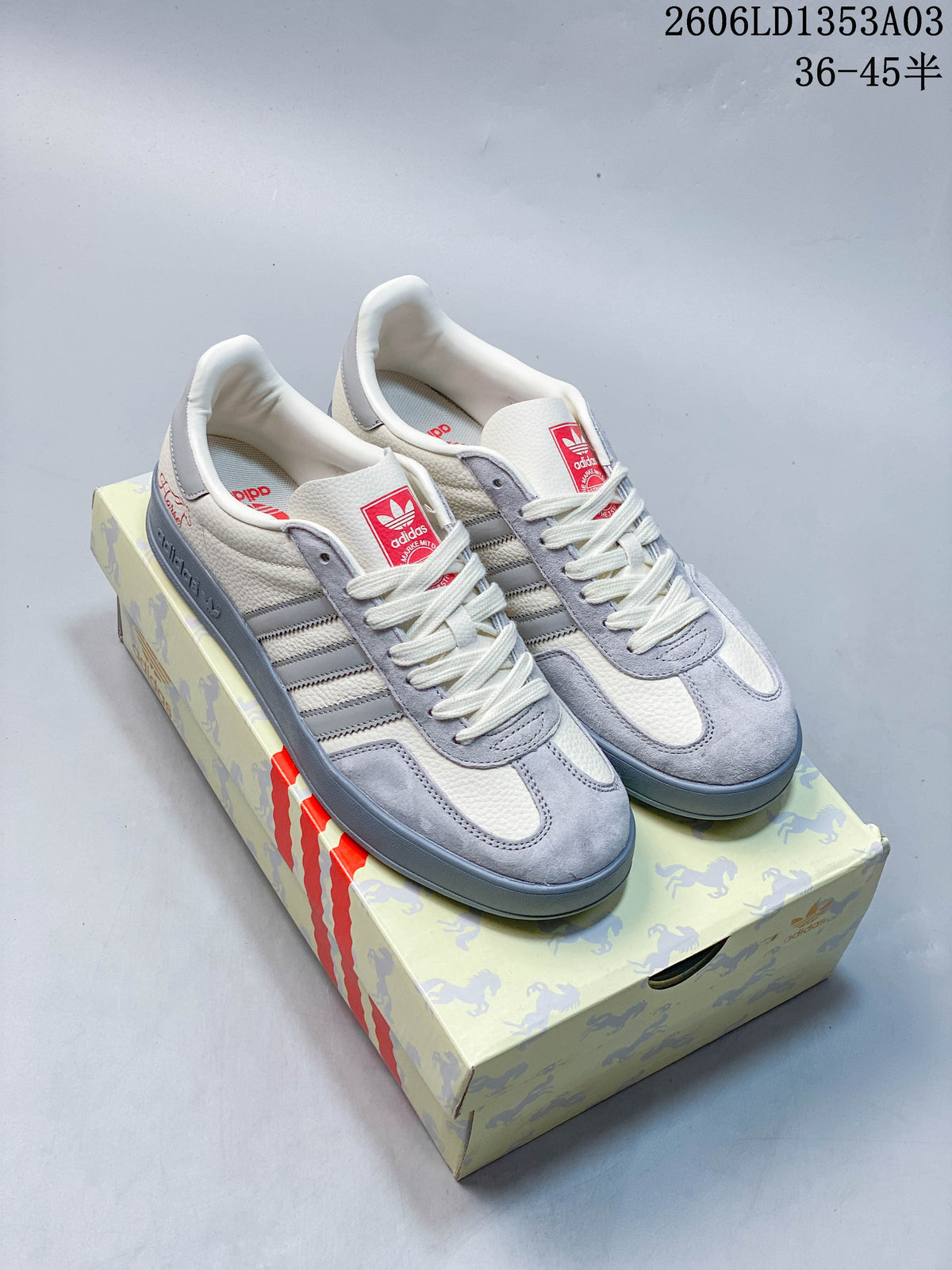 Pair of white and grey Adidas Originals Gazelle Indoor sneakers beside horse-patterned packaging