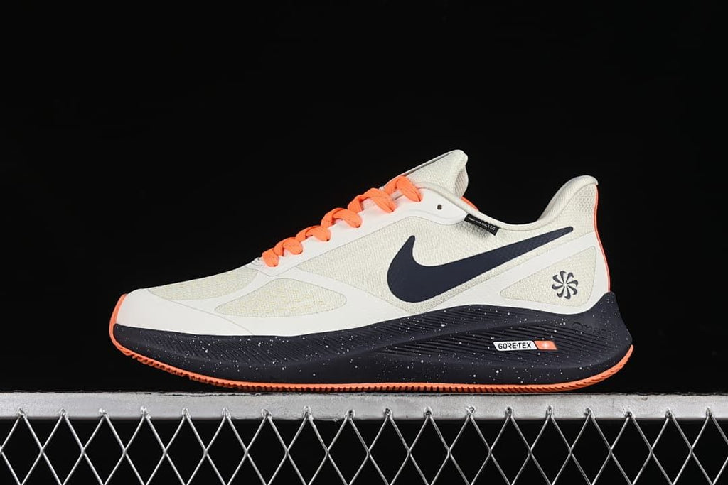 Side view of off-white Nike Zoom Winflo 7 shoes with navy accents, orange laces, and speckled dark midsoles