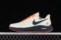 Side view of off-white Nike Zoom Winflo 7 shoes with navy accents, orange laces, and speckled dark midsoles