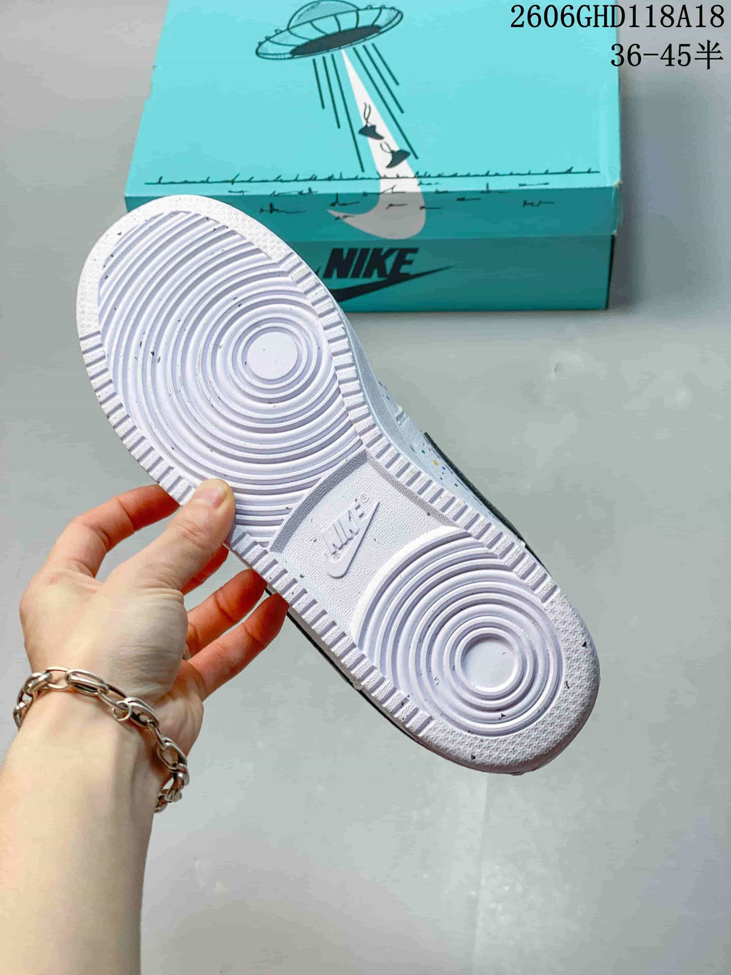Underside of the white sneaker showing a circular-pattern rubber outsole