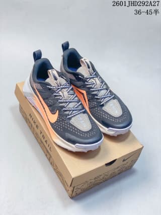 Pair of dark gray and orange Nike trail running shoes displayed on a shoe box.