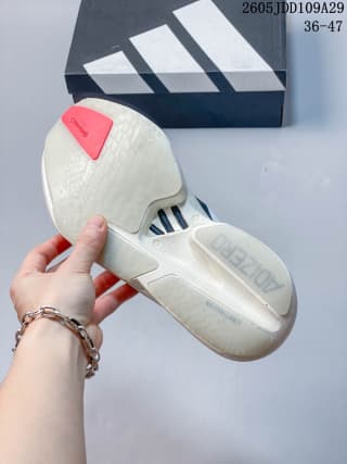 View of the white Adidas running shoe outsole and heel beside an Adidas shoe box, with the style code and size range visible above.